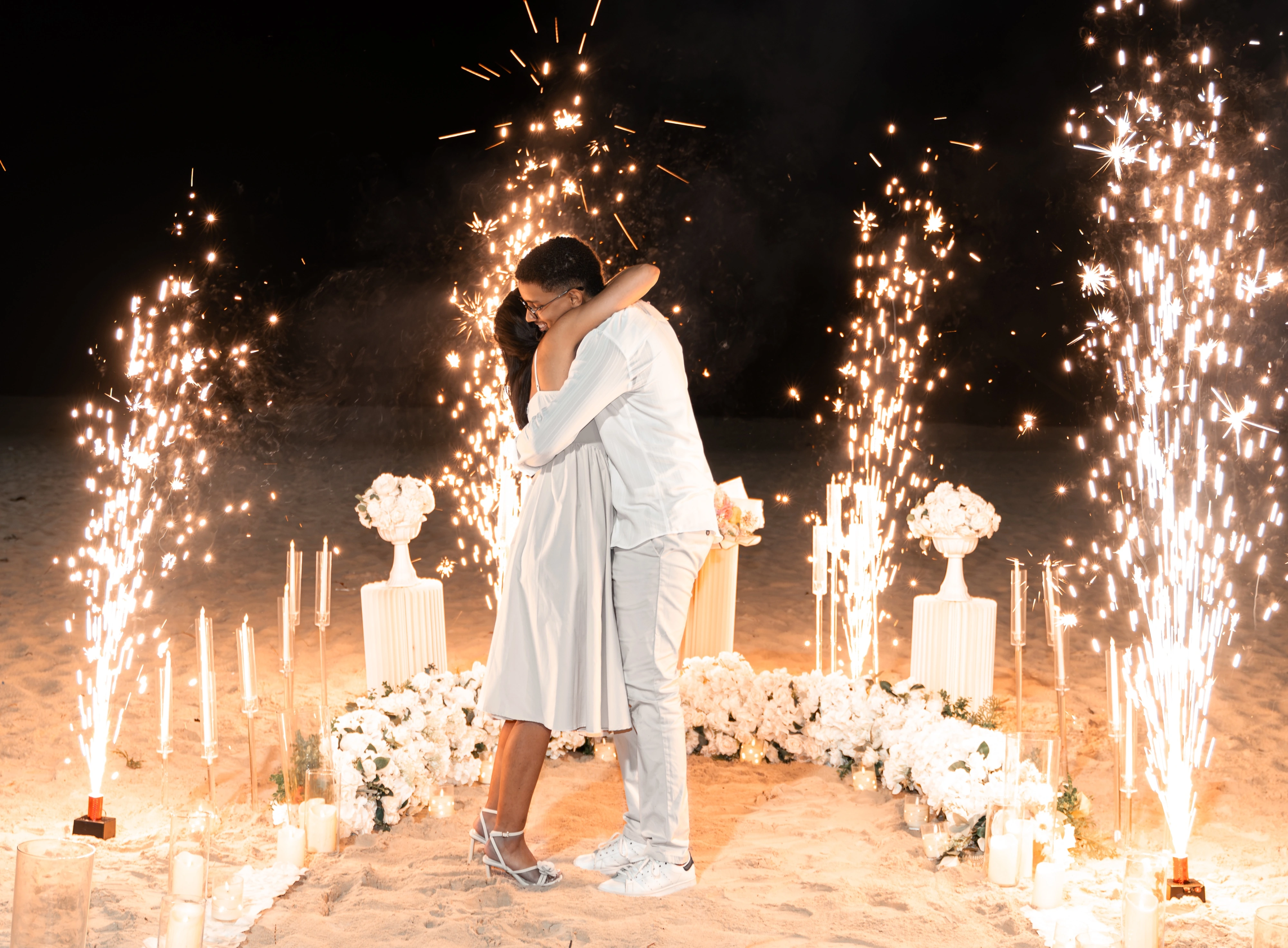 Moises y Sashalee se abrazan rodeados de flores y luces.