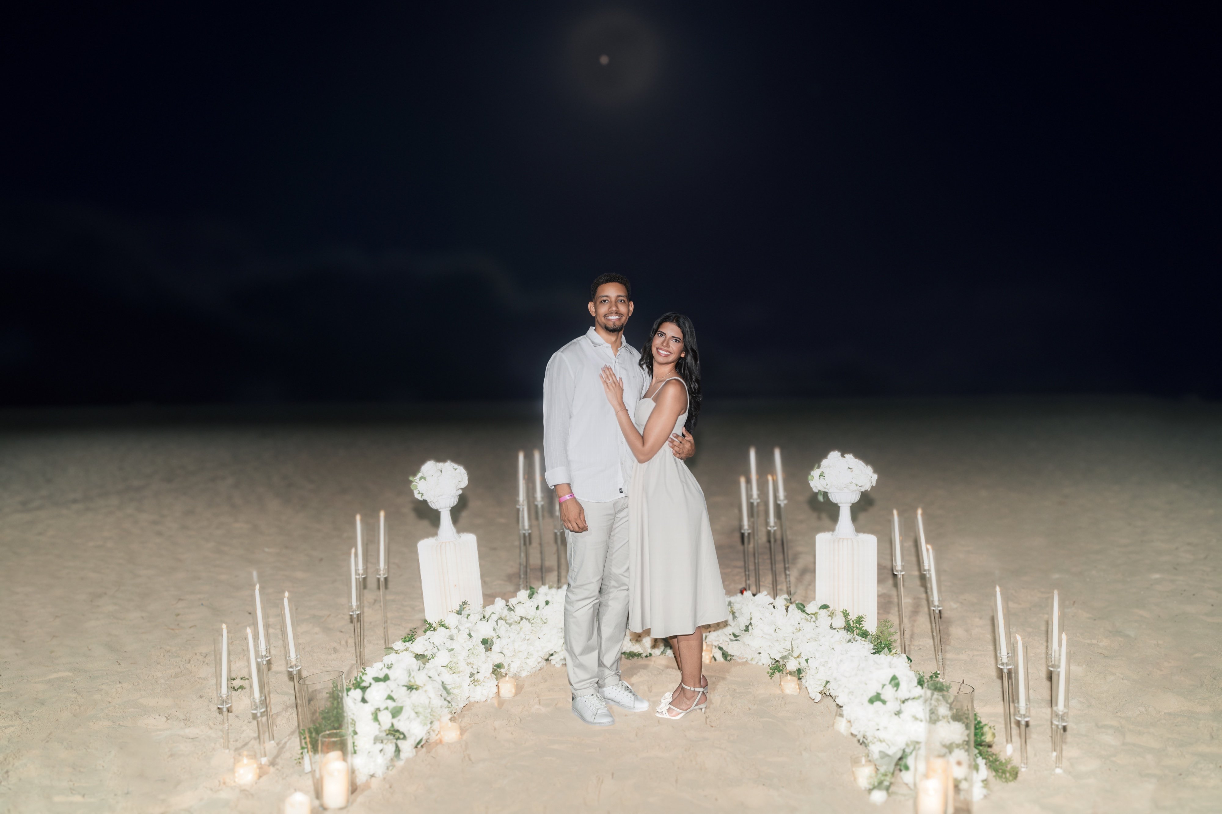 Moises y Sashalee sonríen juntos entre las velas y las flores.
