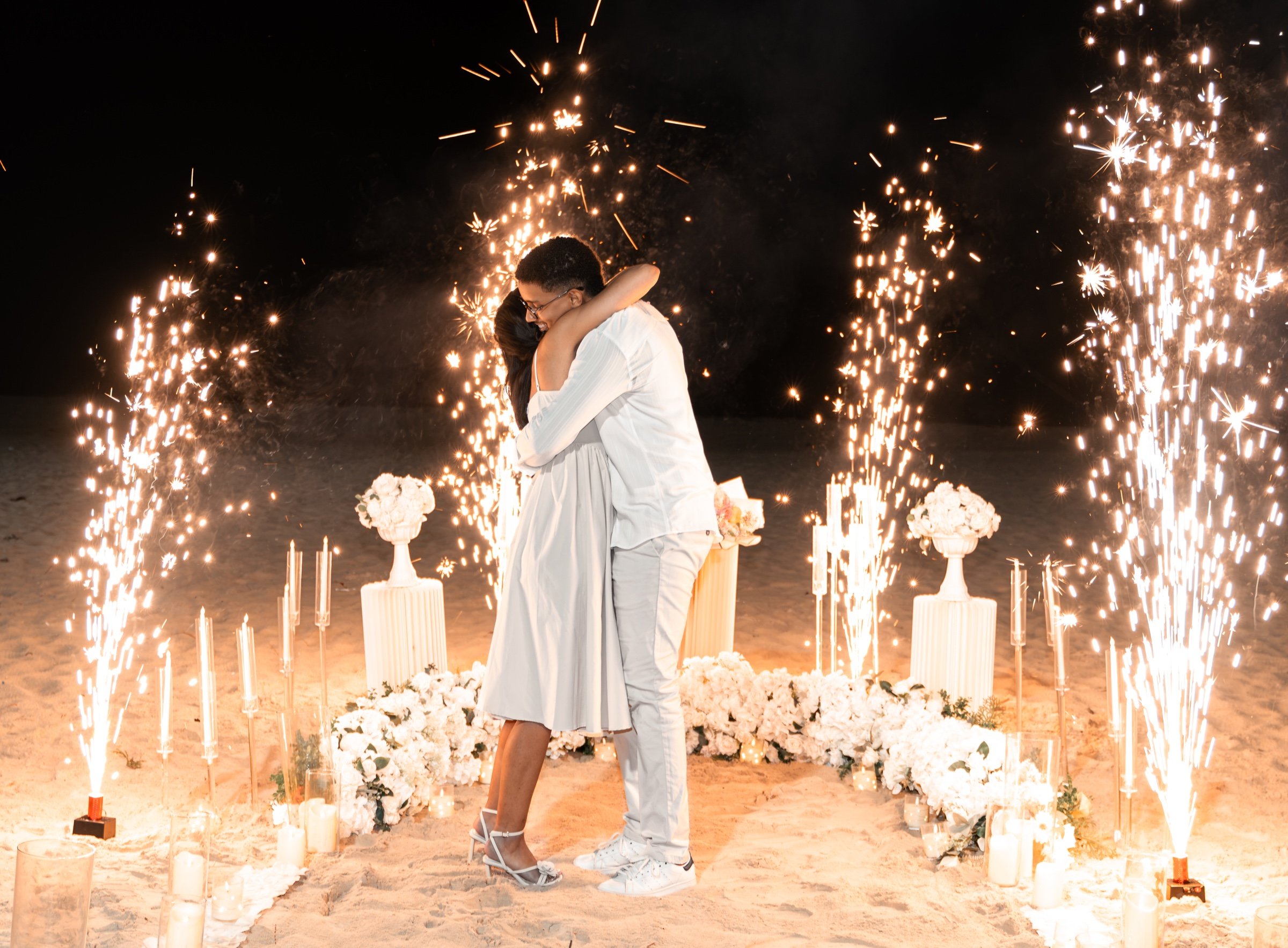 Moises y Sashalee se abrazan rodeados de flores y luces.